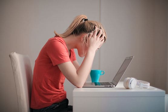 A woman holding her head in her hands in frustration considering how to get unstuck