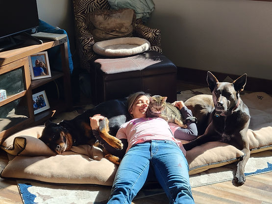 Kori lying on the floor with all of her fur babies, grateful for what she has learned from her emotional eating.