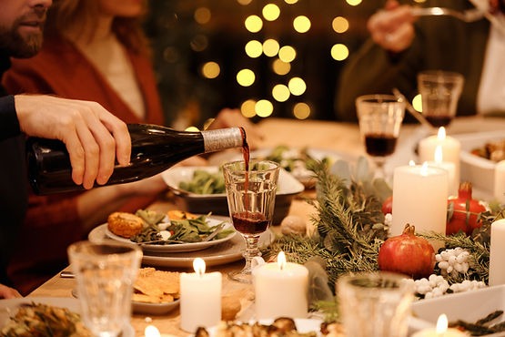 A beautifully set holiday table with a person pouring a glass of wine