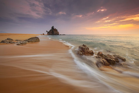 A shoreline with dreamy waves and a sunset