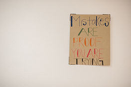 A sign hanging on the wall that says "mistakes are proof you're trying."