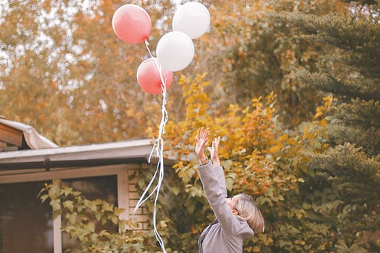 A woman letting go of a bunch of balloons