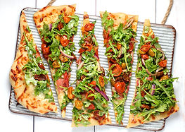A vibrant pizza with tomatoes and arugula
