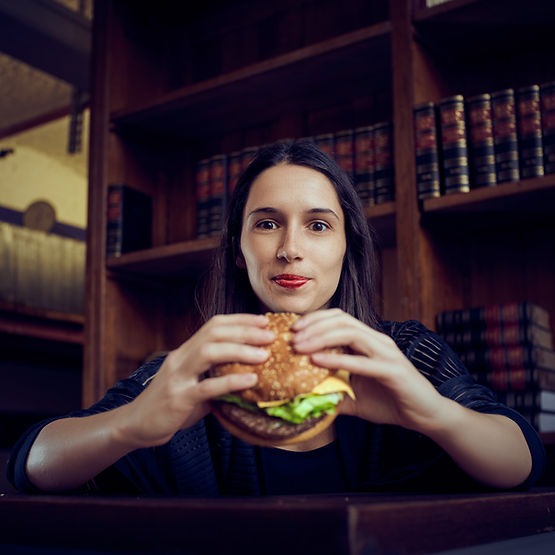 A confident woman holding a burger and changing her unhealthy relationship with food