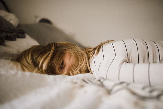 A woman lying face down on her bed, exhausted