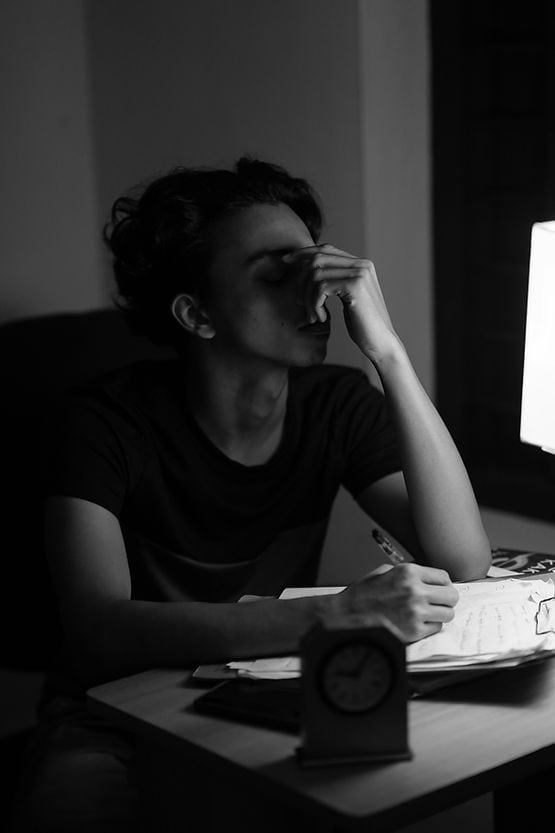 A woman sitting at her computer with her hand to her face, feeling burnt out and overwhelmed from the mental load