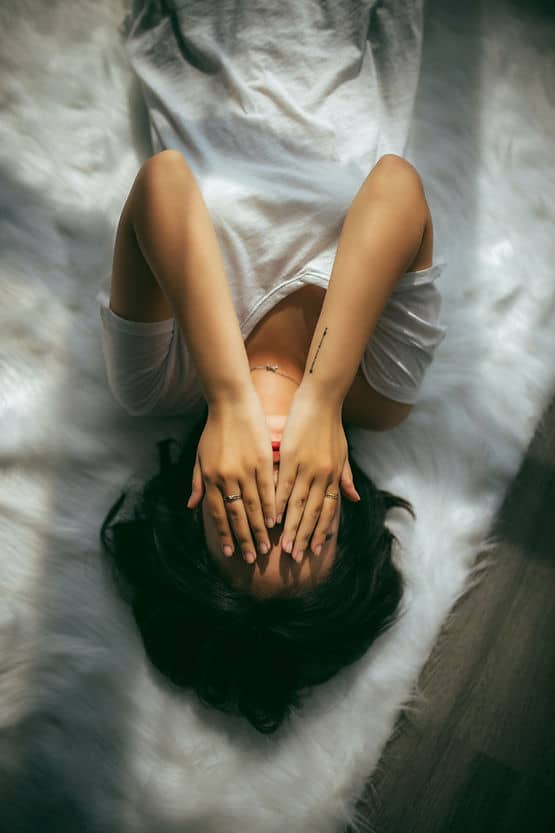 A woman lying down with her hands over her face