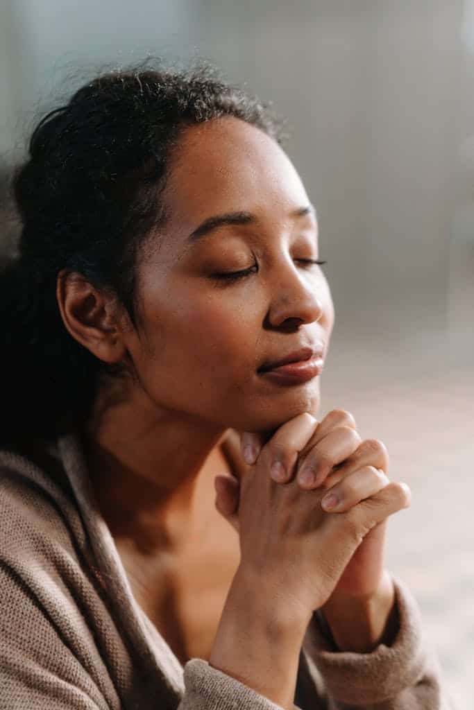 Close-up of a woman praying, conveying a sense of peace and self-connection as she stays with herself when she speaks her truth without guilt.