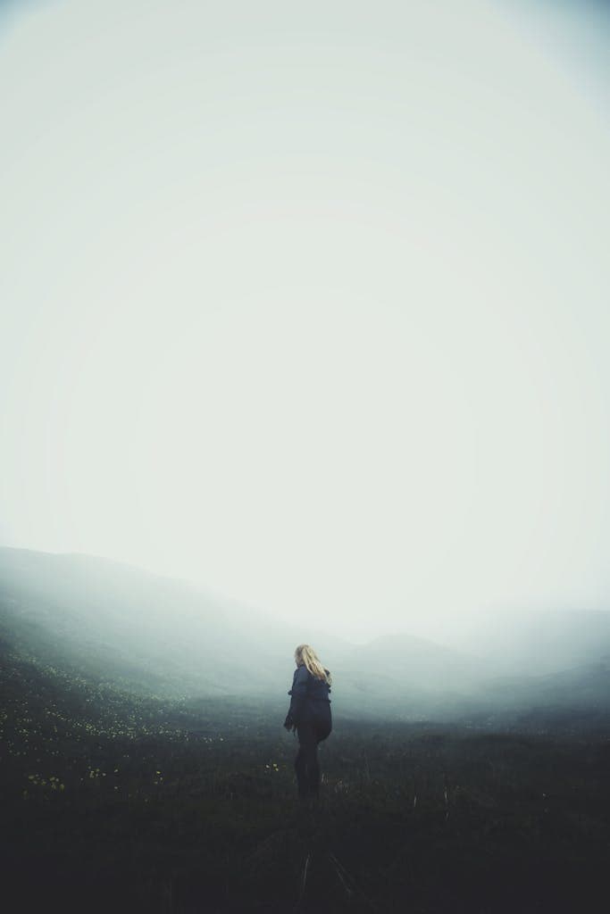 A solitary woman walks through a foggy landscape in Binn, Switzerland, creating a moody atmosphere.